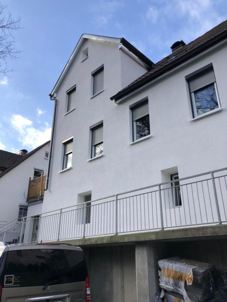 Sanierte Hausfassade mit neuen Fenstern und Rollläden